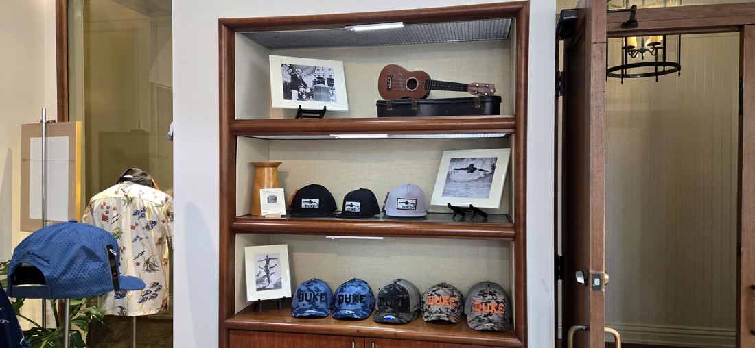 A wooden cabinet of caps and framed photographs.